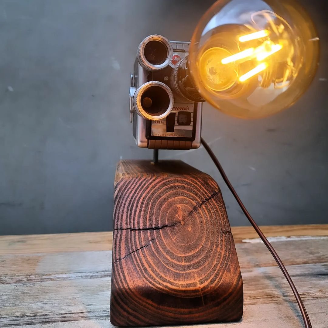 A vintage camera repurposed into a unique lamp with a glowing filament bulb