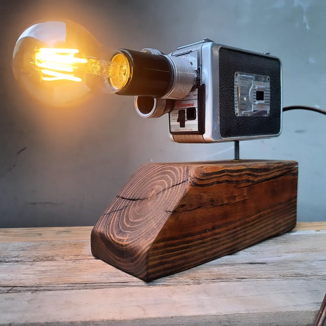 A unique table lamp fashioned from a vintage camera mounted on a wooden base