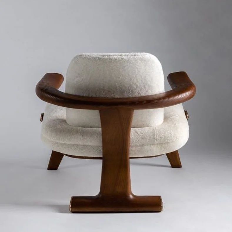 A vintage-style chair with plush white upholstery and a unique wooden T-shaped base.