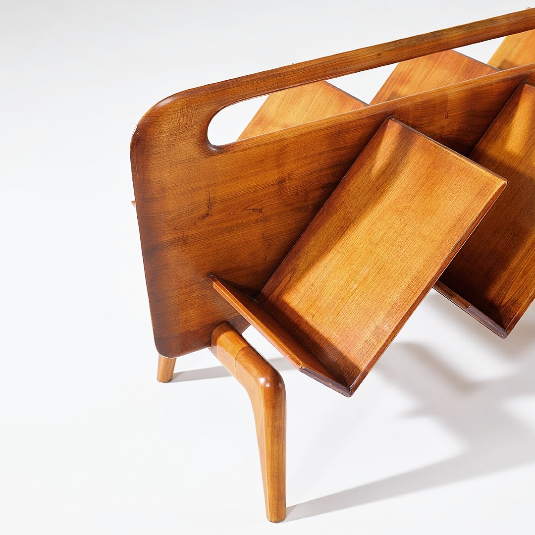 A vintage wooden magazine rack with a sleek design and smooth curves.