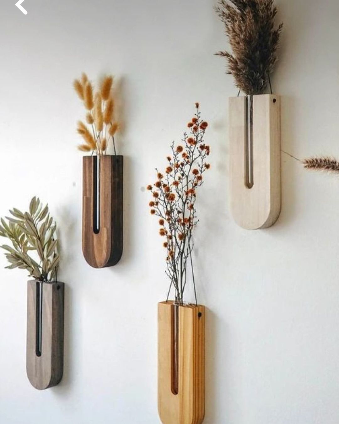 Wall-mounted wooden vases with arrangements of dried plants