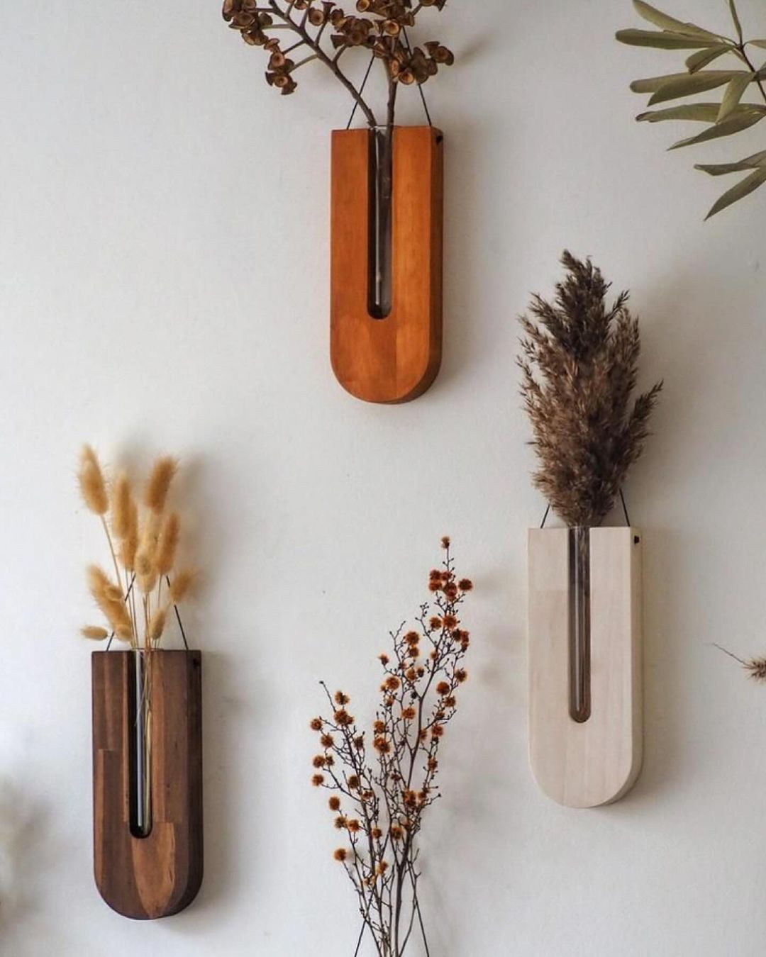 Wall-mounted wooden vases with dried plants