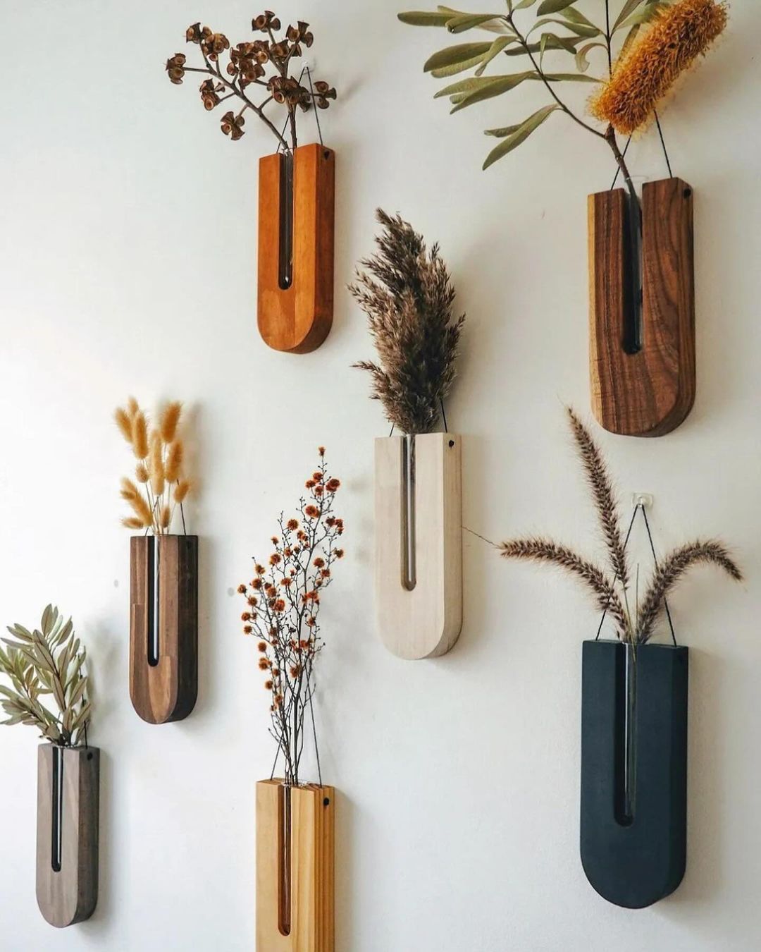 Wall-mounted wooden vases with dried plants