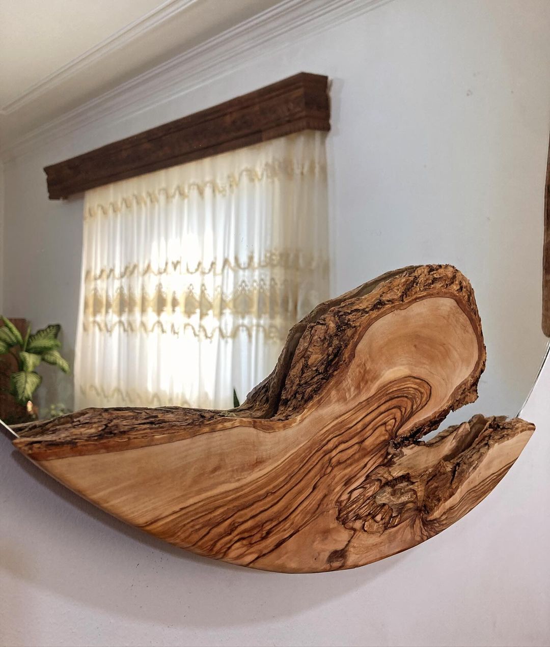 A wave-shaped wooden wall mirror adding natural flair to the room.