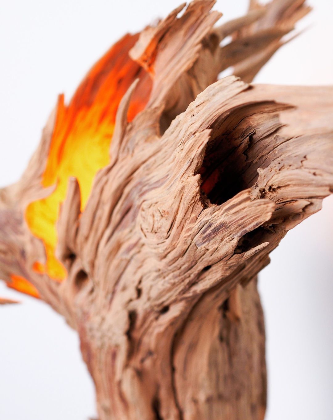 A weathered piece of driftwood with a fiery glow depicting warmth and aging