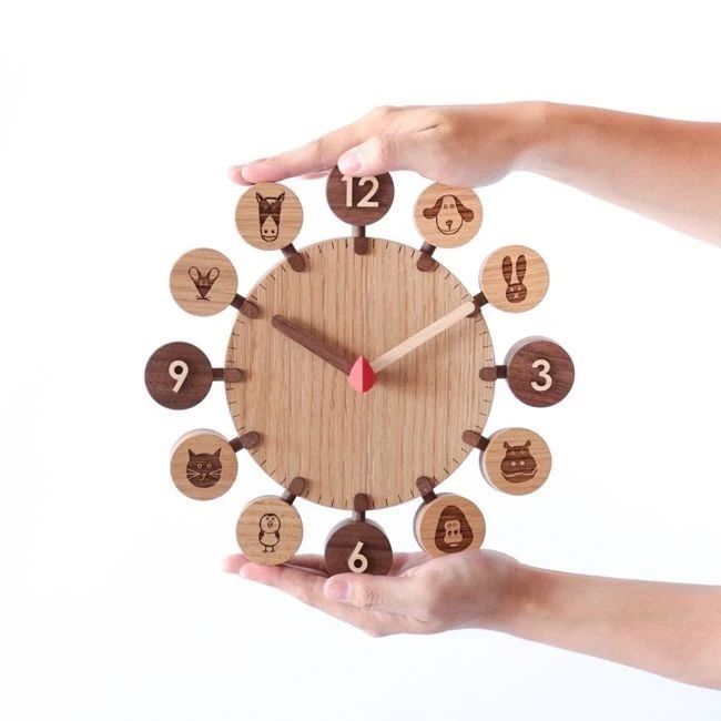 A whimsical wooden wall clock with animal icons representing numbers being held by hands