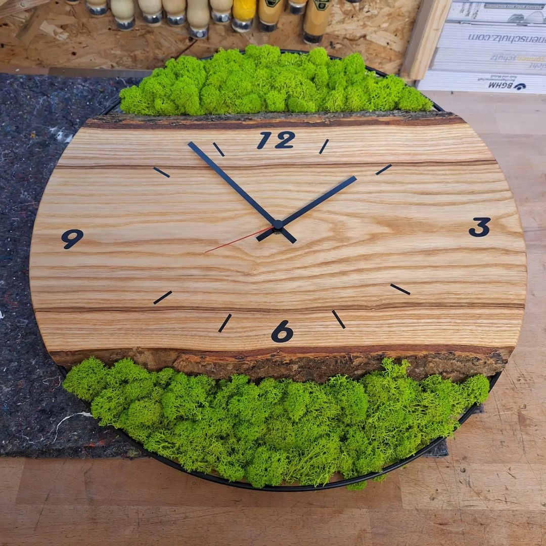 A rustic wooden clock with vibrant green moss on its edge