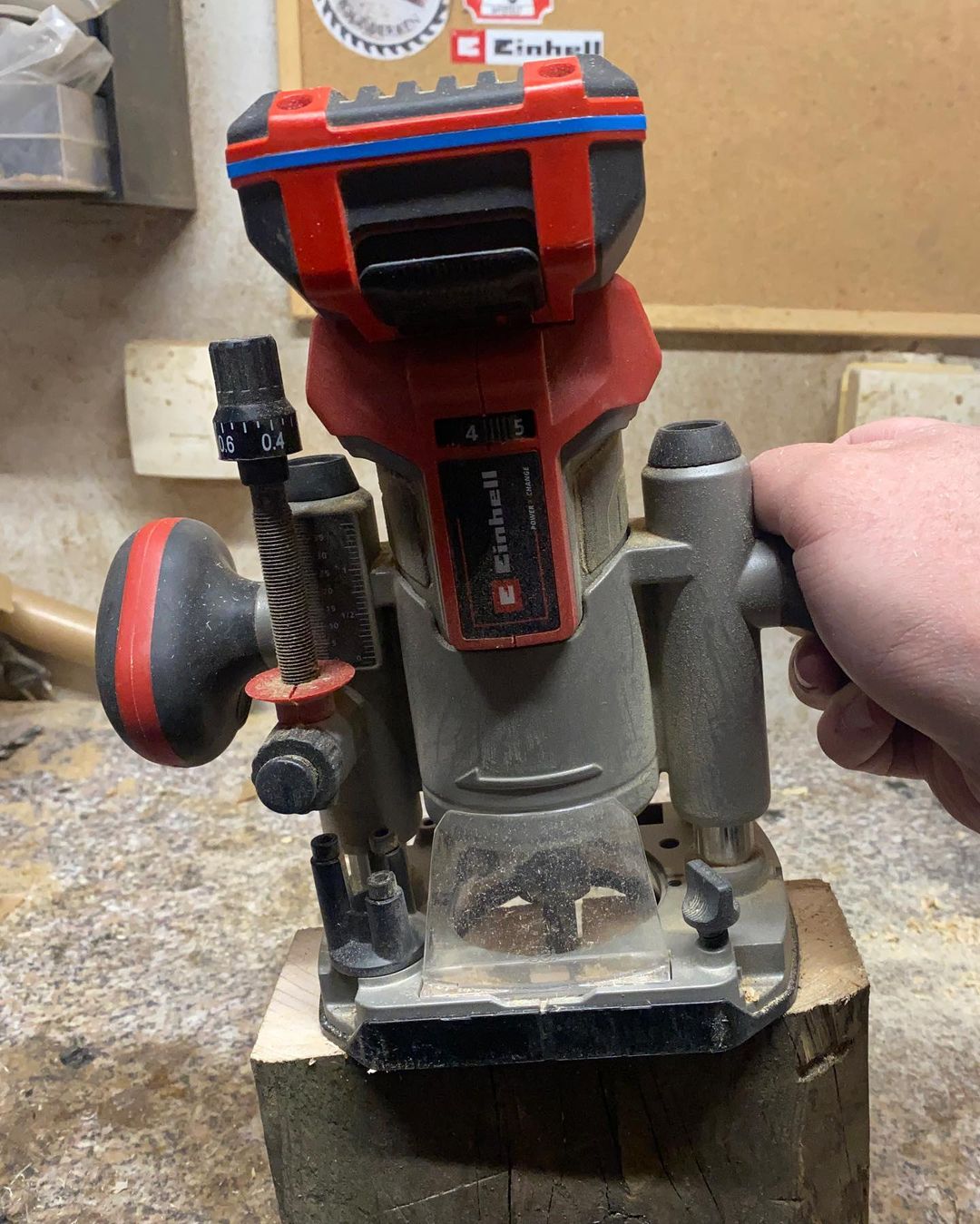 A person operating a powerful red and grey Einhell cordless router on a wooden piece, demonstrating precision in woodworking.