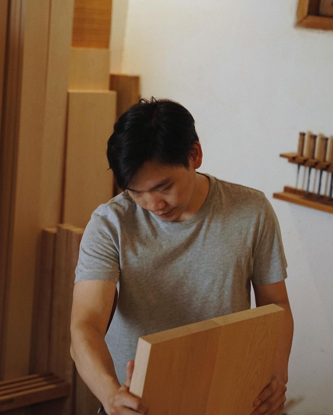 A man intently examining a wooden piece with craftsmanship and precision