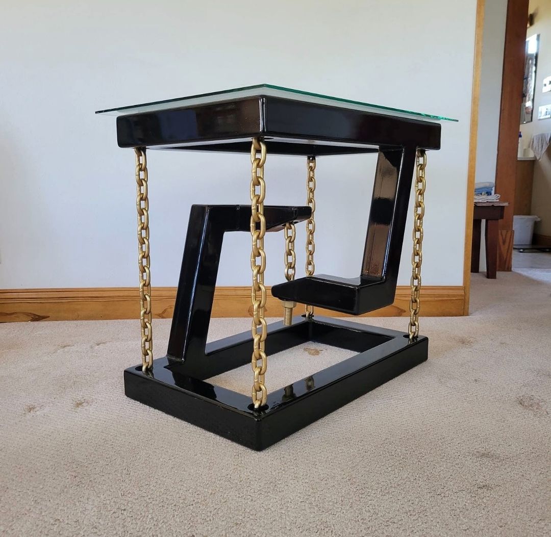 A sleek and unconventional glass-top table supported by gold-colored chains